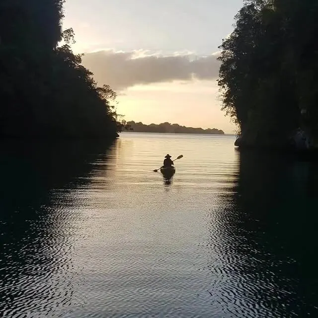 Kayaker paddling at sunset between the cliffs of Los Haitises